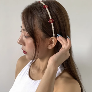 Detailed side view of floral headband with white pearls and red crystal beads on a model