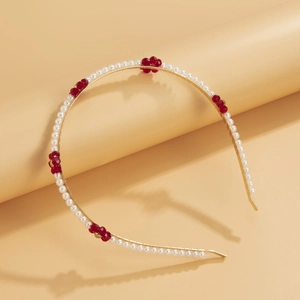 Detailed view of gold metal headband with woven faux pearls and red beaded flowers