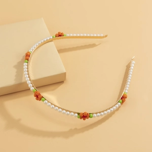Detail showing gold metal headband with white faux pearls and orange daisy bead patterns