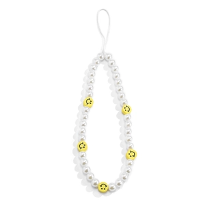 Detail of beaded phone strap with white pearls and yellow smiley face charms on white background