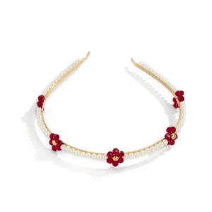 Detail of gold metal headband with white pearls and red crystal flower embellishments
