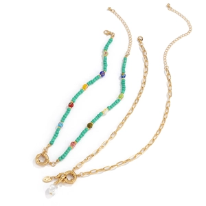 Detail van kleurrijke kralenketting met turquoise accenten en gouden parelhanger