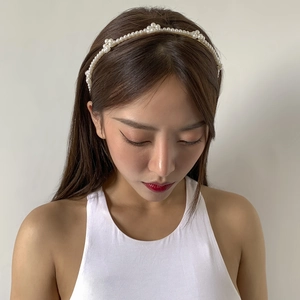 Detail shot of a minimalist gold headband with white pearls worn by a model