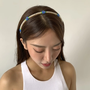 Detail of floral faux pearl headband with blue and green daisy beads on model