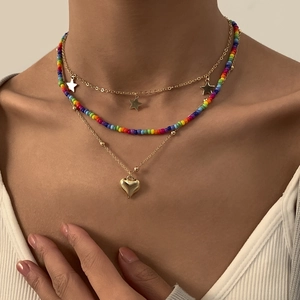 Detail van gelaagde boheemse ketting met regenboogkralen en hartvormige hangers