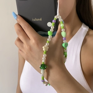 Close-up of beaded phone strap featuring green mushroom, heart and star-shaped charms