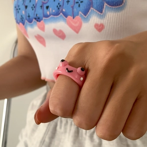 Nahaufnahme eines süßen 3D Froschrings aus pinkfarbenem Harz am Finger im Retro-Stil