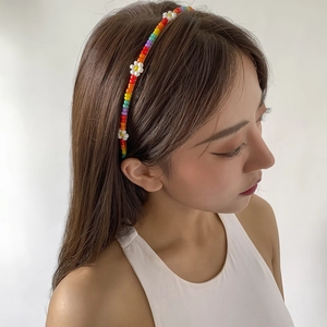 Detail of handmade rainbow beaded headband with delicate white daisy flower accents