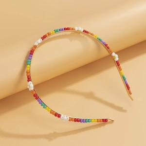 Close-up of golden headband with colorful rainbow beads and white woven daisy flowers