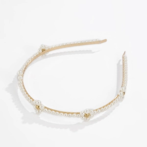Detail of flower-shaped pearls on a gold metal headband for a vintage hair style