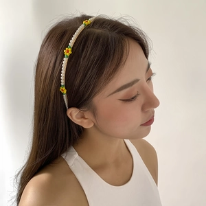 Detail of beaded pearl headband featuring colorful floral accents on a slim white band