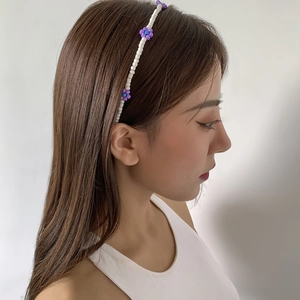 Boho style woven daisy beaded headband with purple and blue flowers on model