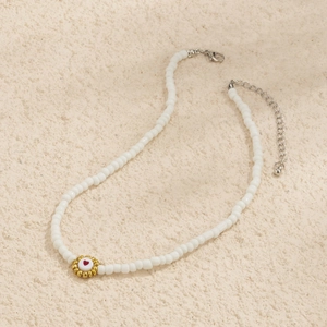 Detalle de collar de cuentas hecho a mano con colgante de corazón dorado y cierre de langosta