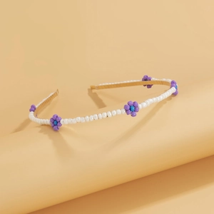 Close-up of handmade beaded daisy headband with white and purple beads on gold frame