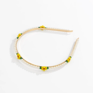 Detail of a thin gold metal headband featuring white pearls and colorful beaded flowers