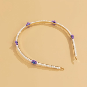 Macro shot of hand-woven purple bead flowers on a white beaded metal headband