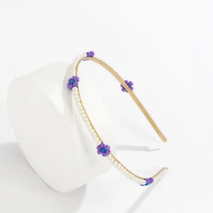 Detail of floral headband with purple beaded daisies and white pearls on gold metal frame