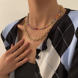 Detail van gouden ketting en kleurrijke boho kralenketting gedragen door een model
