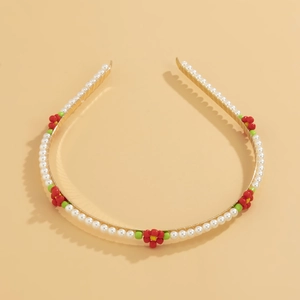 Detail view of pearl headband with red and green beaded flower accents on gold frame