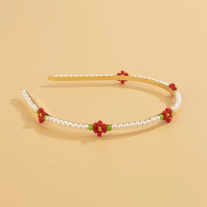 Detail of gold metal headband featuring white pearls and colorful beaded daisy flowers