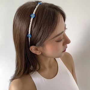 Close-up of a handmade woven daisy headband with blue beads worn by a female model