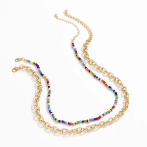 Detail van de kleurrijke boheemse kralenketting en gouden schakelketting met karabijnsluiting