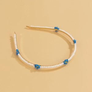 Detail of beaded daisy headband with white pearls and blue flowers on gold base
