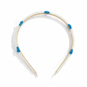 Macro detail of hand-beaded white seed pearls and blue flowers on a slim gold headband
