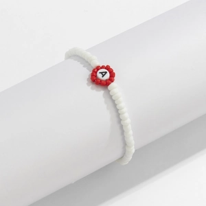 Detalle de pulsera de cuentas blancas con una flor roja y una cuenta con la letra A negra