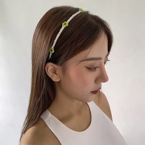 Detail view of handmade beaded headband with white beads and red floral accents