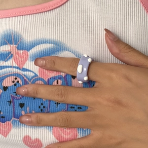 Nahaufnahme eines lavendelfarbenen Harzrings mit weißen 3D-Punkten am Finger