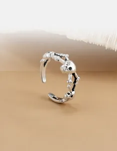 Detail van zilveren schedel teenring met gotisch punkontwerp en botvormige schakels