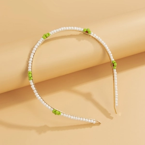 Detailed close-up of handmade green daisy beads on a slim golden metal floral headband