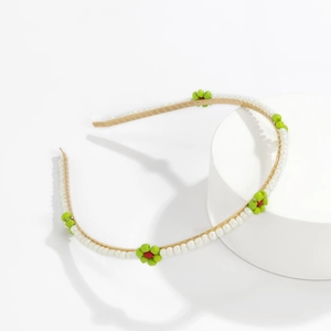Detail of beaded daisy headband with white faux pearls and green floral accents
