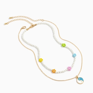 Detail van kleurrijke kralenketting met bloemen en yin yang hanger op gouden ketting