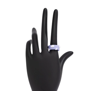 Detail eines hellvioletten Harzrings mit weißen Punkten auf einem schwarzen Ständer