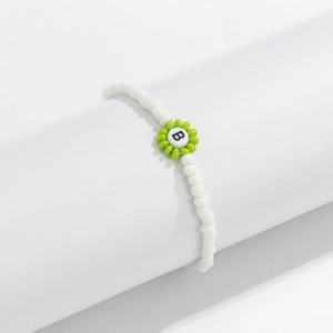 Detalle de pulsera de cuentas blancas con flor verde y cuenta con la letra B central