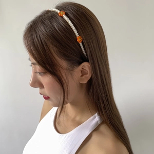 Detail of hand-beaded daisy headband with white faux pearls and orange flower accents