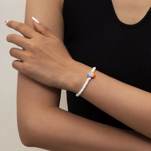 Pulsera de cuentas de colores con flor arcoíris y letra C en una muñeca femenina