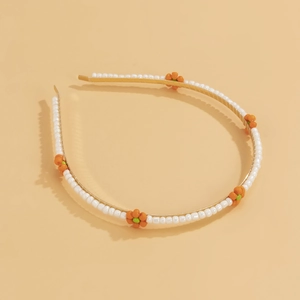 Close-up of golden headband with woven white beads and orange daisy floral accents