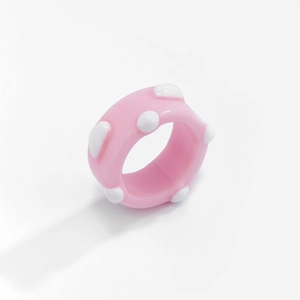 Nahaufnahme eines klobigen Harzrings in Rosa mit weißen Polka Dots und Glanzfinish