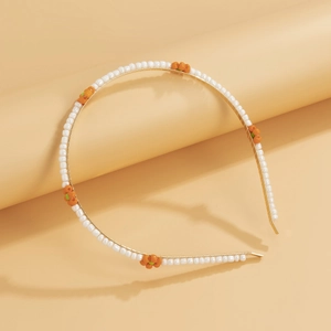 Detailed view of woven daisy beads on a thin gold metallic headband with orange accents