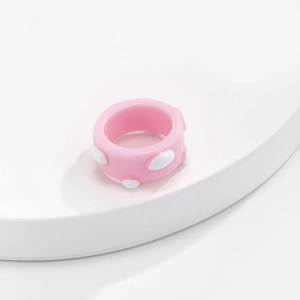 Nahaufnahme eines rosa Harzrings mit weißen Punkten und süßem, minimalistischem Design