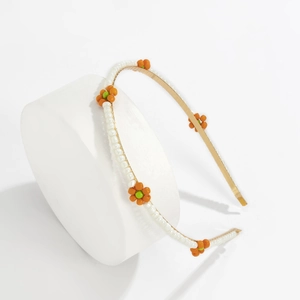 Detail of gold metal headband with white faux pearls and yellow beaded flower accents