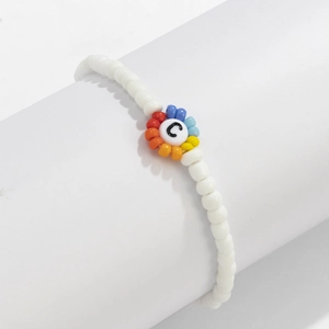 Primer plano de pulsera de cuentas blancas con flor de arcoíris y cuenta de letra C