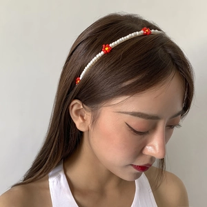 Detail of handmade woven daisy headband with white beads and red-yellow flower beads