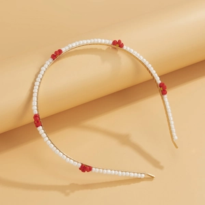 Detail of woven flower headband with red beads and white pearls on gold metal frame