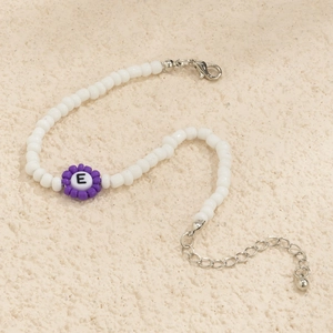 Detalle de pulsera de cuentas de colores con flor púrpura y colgante con la letra E