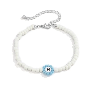 Detalle de pulsera de cuentas con dije de flor azul y letra H sobre fondo blanco