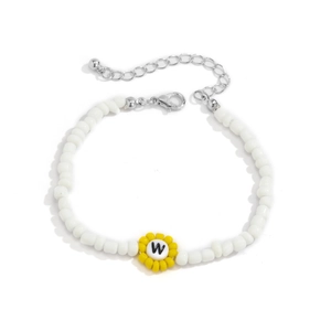 Detalle de pulsera de cuentas blancas con dije de girasol y cuenta negra con la letra W